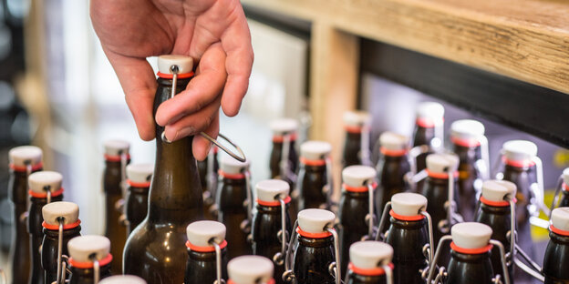 Hand greift nach einer braunen Flasche mit Bügelverschluss