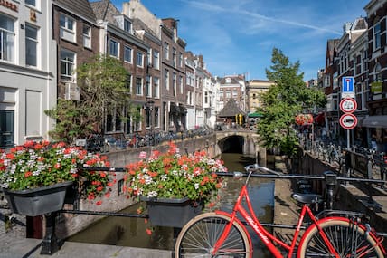 Gracht in Utrecht mit rotem Fahrrad im Vordergrund.