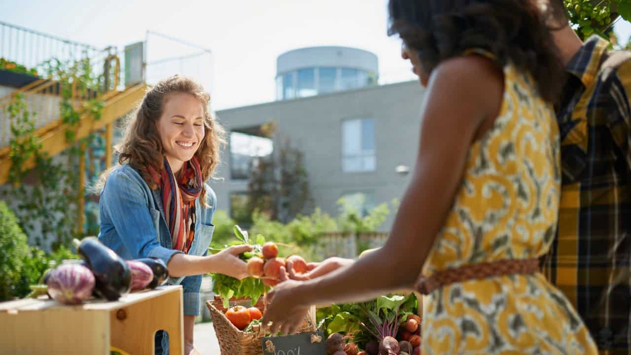 Friendly woman tending an organic vegetable stall at a farmers market