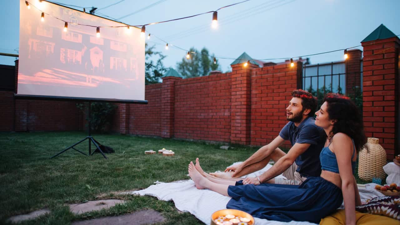 Couple in love watching a movie, in twilight, outside on the lawn