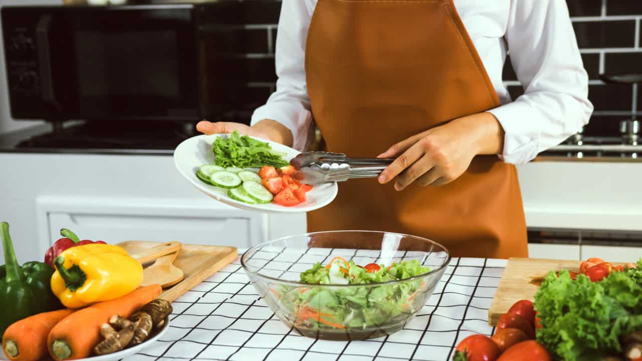 Asian woman is pouring ingredients that are prepared to make a salad