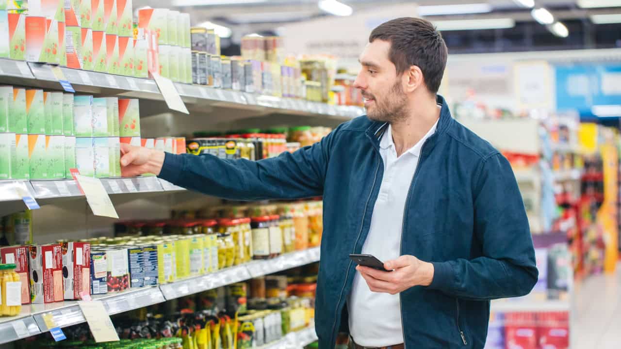 At the Supermarket: Handsome Man Uses Smartphone