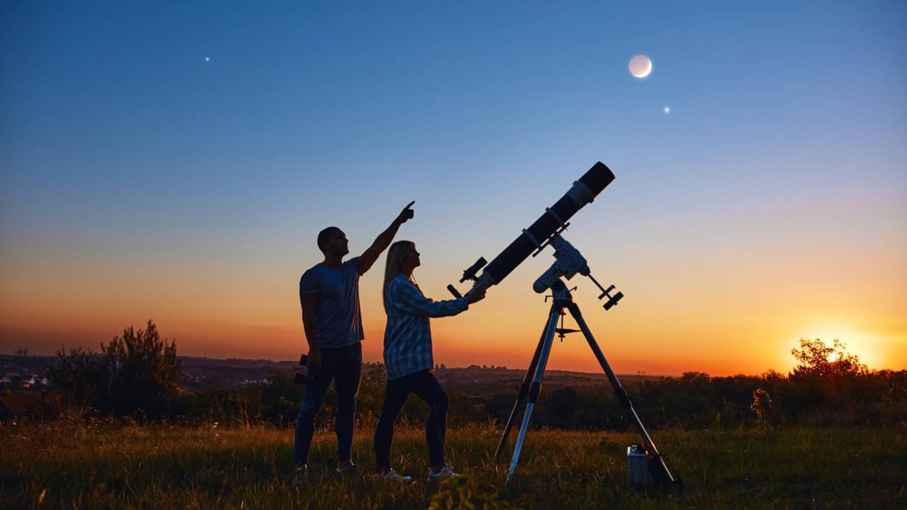 Couple stargazing together with a astronomical telescope