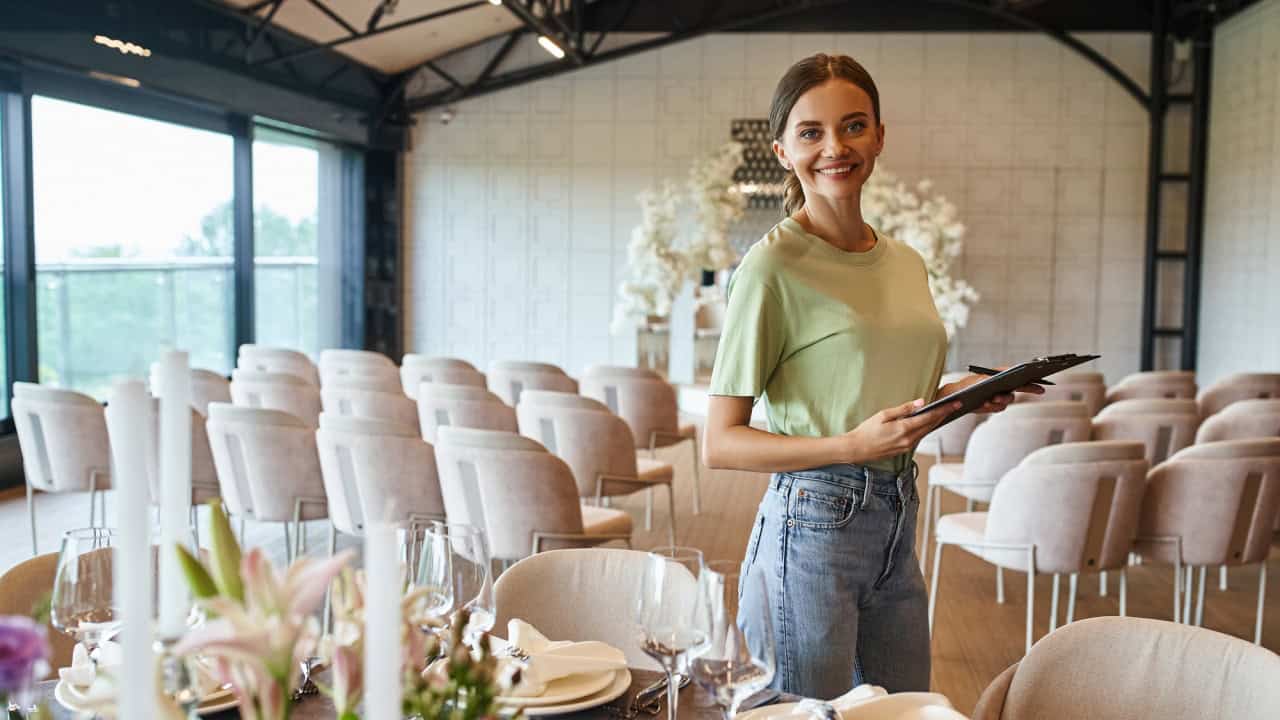 Happy event manager with clipboard smiling at camera