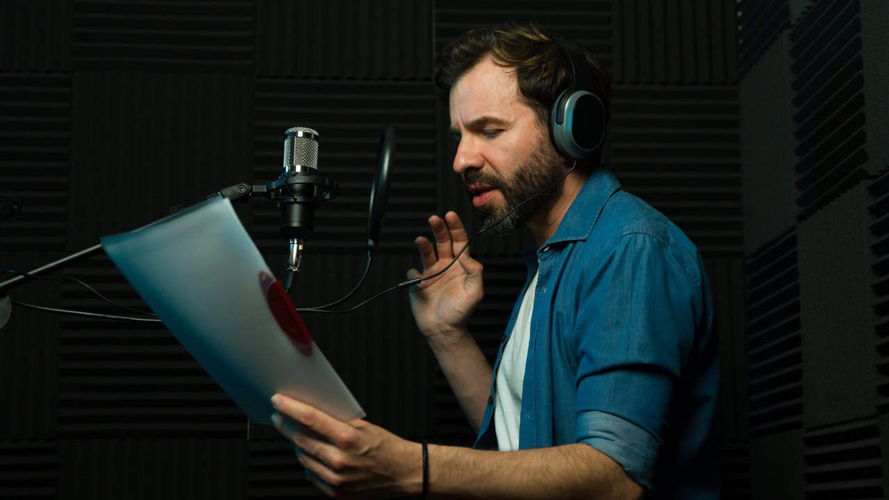 Male voice actor with headphones performs in a soundproof recording