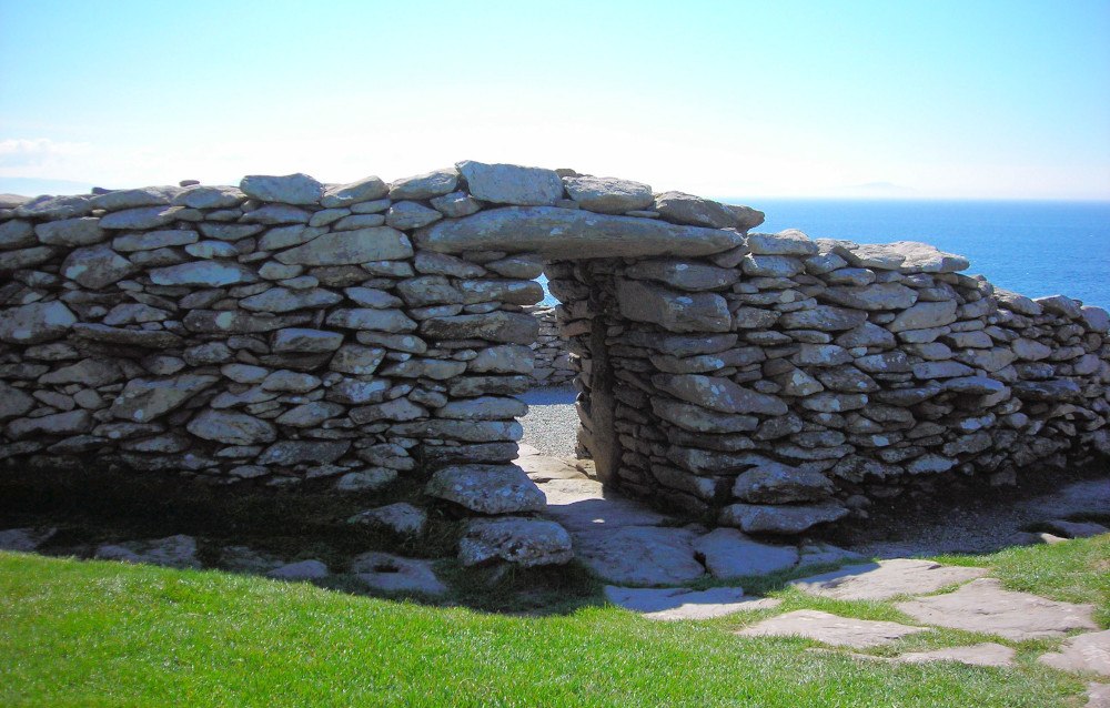 A close-up of the stone walls of Dunbeg fort with a clear blue sky and sea behind.