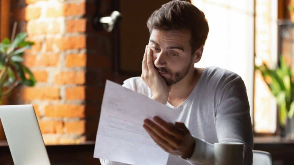 Confused frustrated young man reading letter in cafe, debt notification, bad financial report, money problem, money problem, upset student receiving bad news, unsuccessful exam or test results