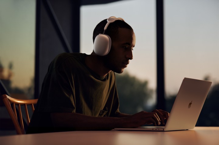 A MacBook user wearing Apple AirPods Max headphones.