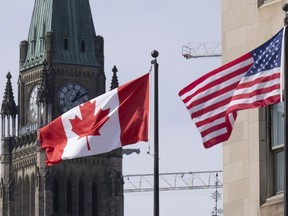 Canadian and United States flags are seen flying near Parliament Hill, Wednesday, March 22, 2023 in Ottawa.