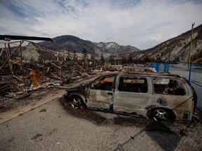 The remains of a large structure and vehicles destroyed by the Lytton Creek wildfire are seen on the side of the Trans-Canada Highway near Lytton, B.C., on Aug. 15, 2021.