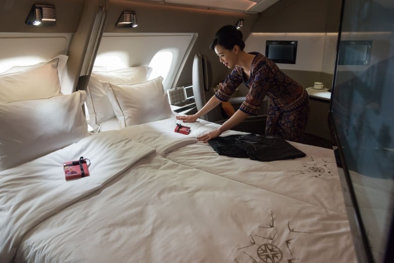 A woman makes a bed aboard an airplane