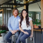 Chip and Joanna Gaines sitting outside of a house