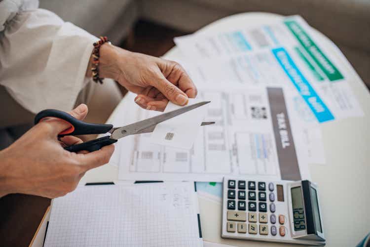 Woman cutting her credit card at home, she is in debt and can pay the bills and taxes