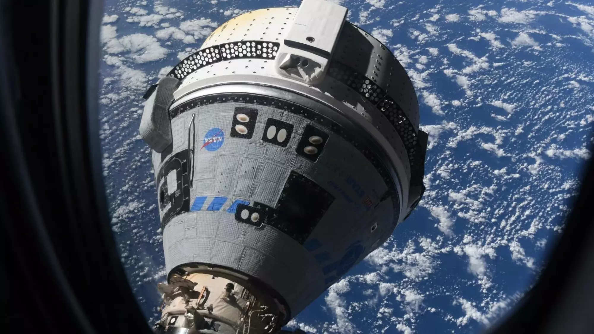 An empty Starliner spaceship docking at the International Space Station