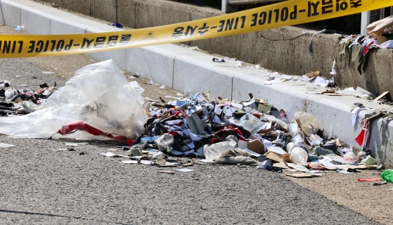 A pile of trash sits on a road beside a torn balloon.