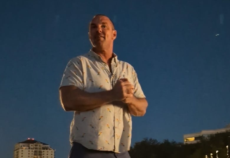 A man stands on a pedestal at night, rallying a crowd of people. 