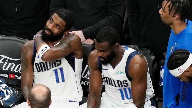 Two men's basketball player sit on the bench.