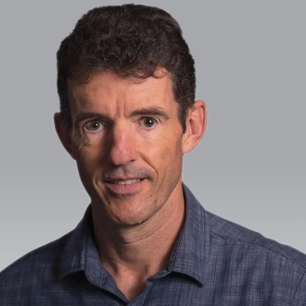 Portrait of a brown haired man in a dark blue shirt.