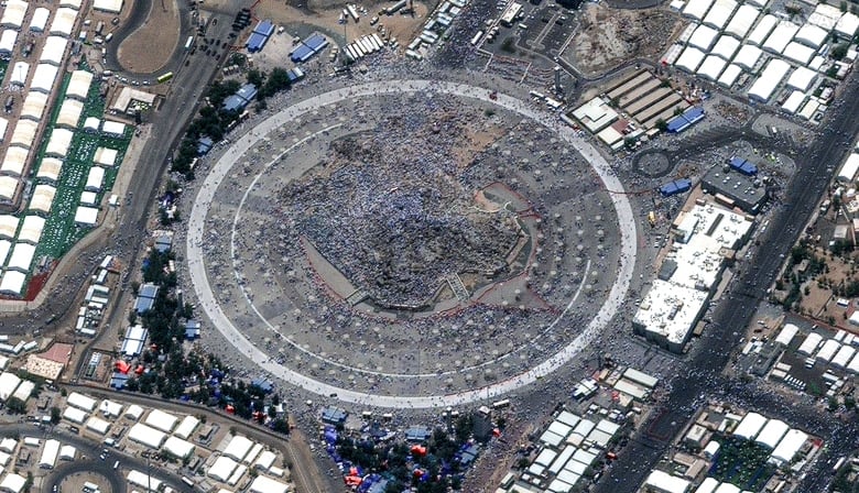 An aerial view shows a structure with untold numbers of people seen in miniature.