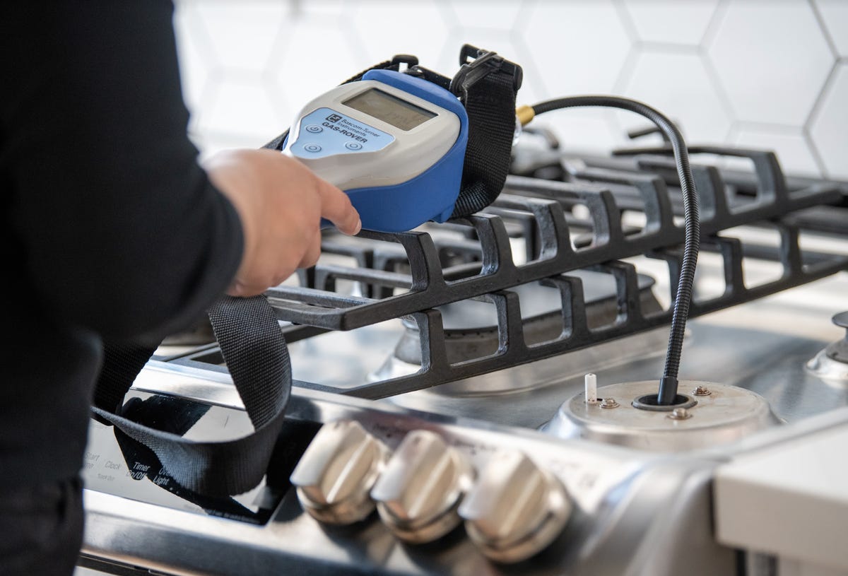 person testing gas stove holding a device