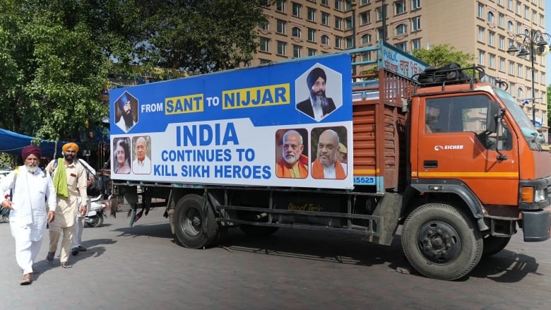 A truck sits outside a building beside a tree. On its side, it says: 'From Sant to Nijjar, India continues to kill Sikh heroes>"