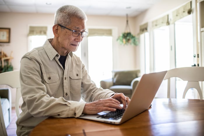 Person typing on laptop at table.